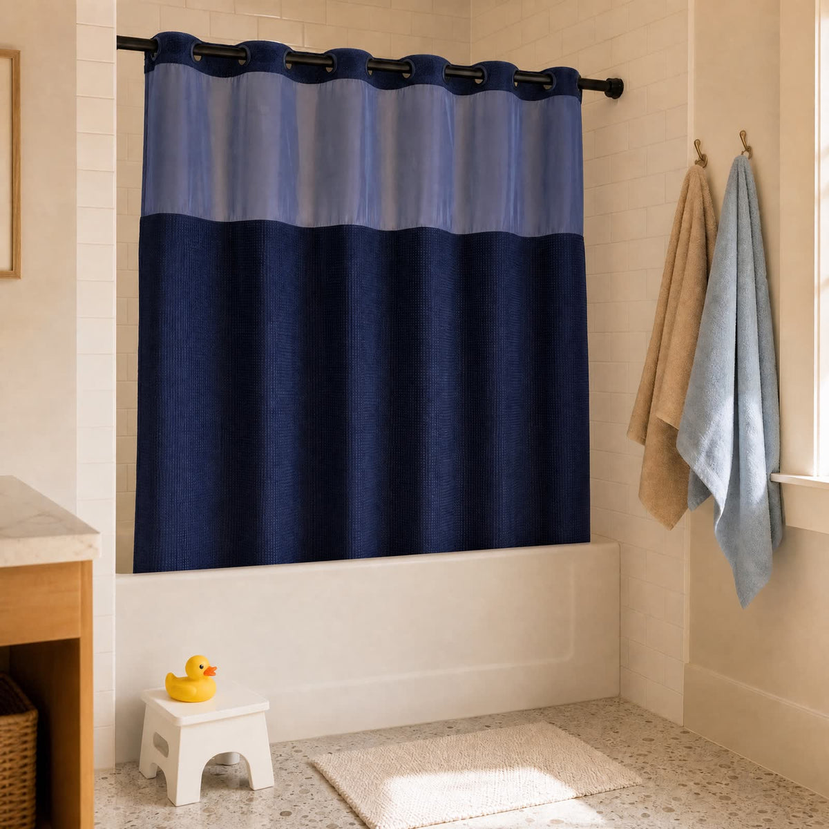 Rideau Aqualis™ bleu marine dans une salle de bain familiale, tabouret d'enfant et canard au pied de la baignoire