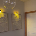 Appliques murales LED Lumora™ allumées dans un salon, une chambre et une cuisine